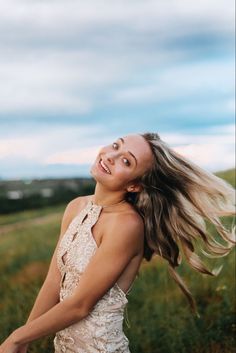 a woman standing in a field with her hair blowing in the wind