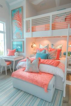 a white bed with pink and blue pillows in a bedroom next to a desk area