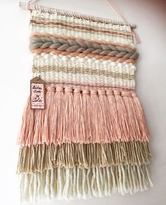 the wall hanging is made out of different colored yarns and has a tag on it