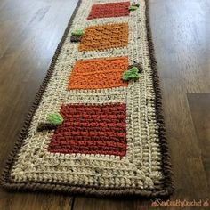 a crocheted table runner with leaves on it sitting on a wooden floor in front of a window