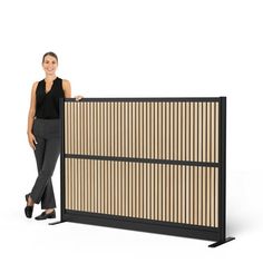 a woman standing next to a tall screen with vertical slats on it's sides