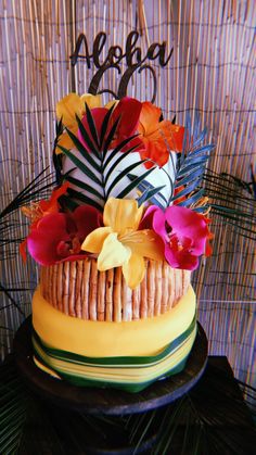 a multi - layered cake decorated with flowers and palm leaves