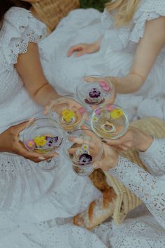 three women are holding wine glasses filled with desserts on them while sitting next to each other