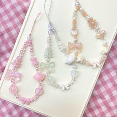 three necklaces are sitting on top of a white tray with pink gingham tablecloth