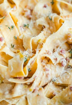 a close up view of a pasta dish with cheese and herbs on top, ready to be eaten