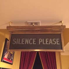 a sign hanging from the ceiling that says,'science please'in front of a red curtain