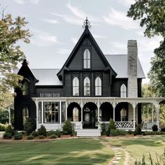 a large black and white house sitting on top of a lush green field