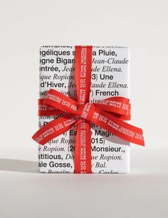 a wrapped gift box with red ribbon tied around the top and bottom, sitting on a white surface