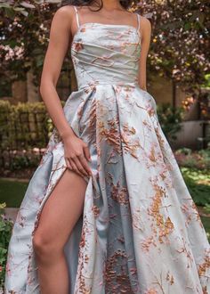 a woman in a white and gold dress posing for the camera with her leg up