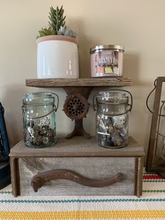 some jars are sitting on top of a wooden shelf next to a potted plant