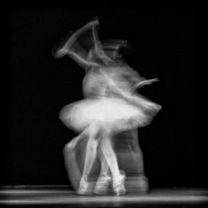 two ballerinas are dancing in the dark