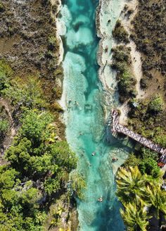 an aerial view of people swimming in the blue water near a bridge over a river