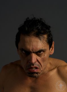 a shirtless man with no shirt on looking at something in his hand and making an angry face