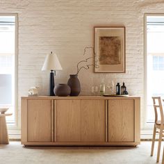 a table with two vases on it in front of a brick wall and chairs