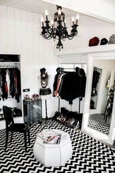 a black and white checkered floor with chandelier in the corner, clothes on hangers