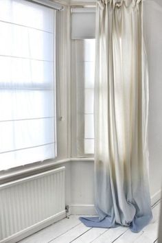 the curtains are pulled back to reveal light coming in from inside an empty room with white walls and wood flooring