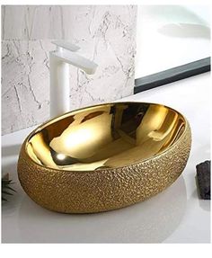 a gold bowl sink sitting on top of a white counter next to a faucet