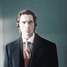 a man in a suit and tie with headphones on his ears looking at the camera