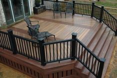 a wooden deck with metal railings and chairs