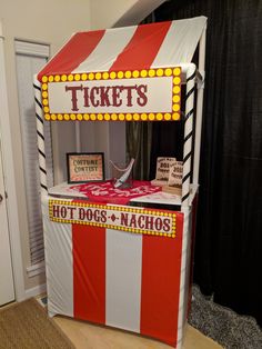 a ticket booth with red and white stripes on the front, hot dogs and nachos written on it