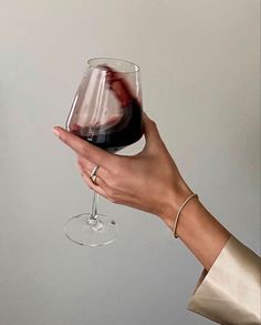 a hand holding a wine glass with red wine in it and the bottom half being held up