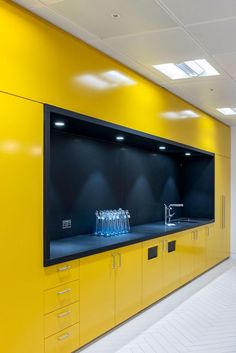 a large television mounted to the side of a yellow wall in a room with lots of cabinets