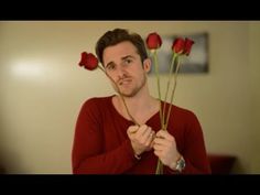 a man holding three roses in front of his face