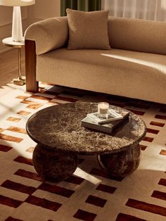 a living room with a couch, coffee table and rug on the floor in front of it