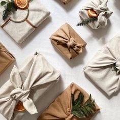 wrapped presents are laid out on a table with oranges and greenery around them