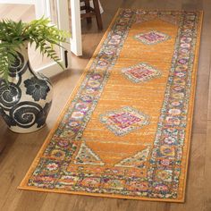 an orange runner rug on the floor in a room with wooden floors and a plant