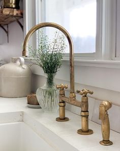 a bathroom sink with two faucets and a vase filled with flowers