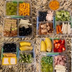 four plastic containers filled with different types of food on a marble counter top next to grapes, strawberries, bananas and other fruits