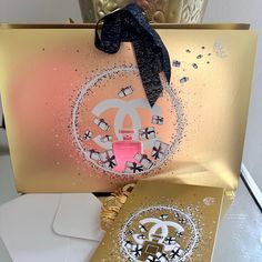 a chanel card with a black scarf on top of it and a gold gift bag