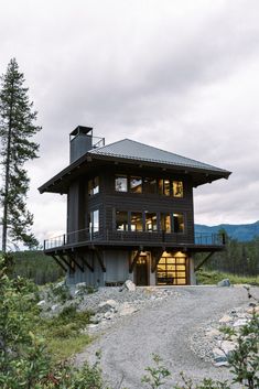 a large black house sitting on top of a lush green hillside next to a forest