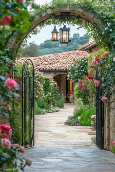 an archway leading to a house with roses growing on the sides and flowers in the front