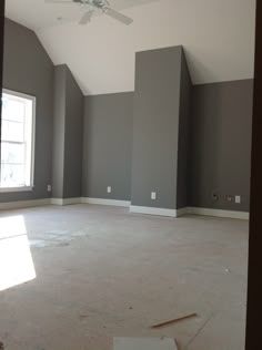 an empty room with gray walls and ceiling fan