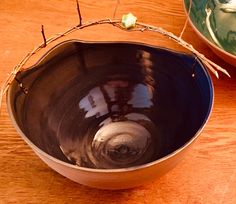 a bowl sitting on top of a wooden table next to another bowl with flowers in it