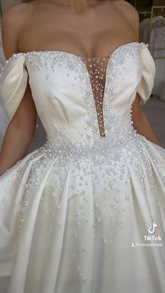 a woman in a white wedding dress with beading on the shoulders and neckline