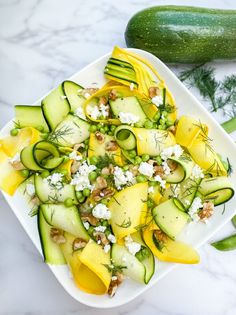 a white plate topped with cucumbers and cheese