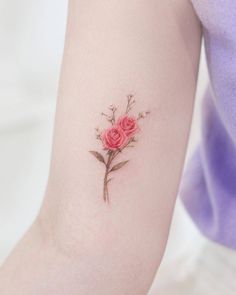 a small pink rose tattoo on the left arm