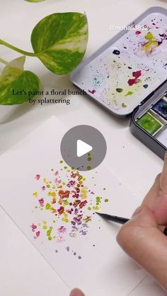 someone is painting flowers with watercolors on paper and using a cell phone to take pictures