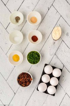 eggs, seasonings and other ingredients laid out in bowls on a white tile floor