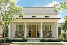 a white house with porches and chairs on the front