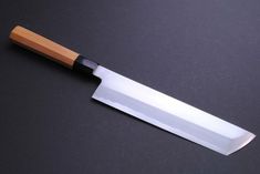 a large knife with a wooden handle on a black surface