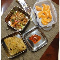 there are four containers with food in them on top of the table, including oranges and rice