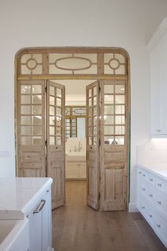 an open door leading into a kitchen with white cabinets and counter tops on both sides