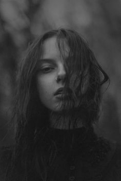 a black and white photo of a woman with her hair blowing in the wind,