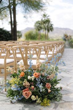 an arrangement of flowers sits in front of rows of chairs