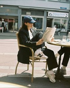 two people sitting at a table reading newspapers