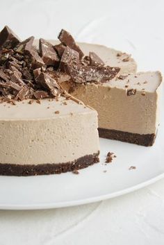 a chocolate cheesecake on a white plate with one slice missing